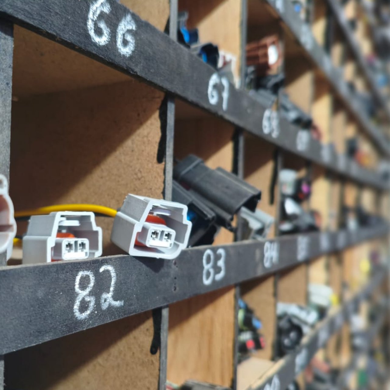 Arnés en fila – Autopartes Eléctricas en Ecatepec Estantería con conectores de arnés organizados, parte de las autopartes eléctricas en Ecatepec